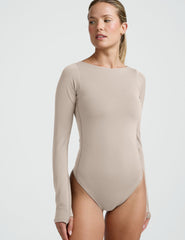 woman wearing a neutral color long sleeve bodysuit.