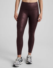 model wearing faux leather maroon leggings on a light gray background.