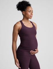 model wearing a purple maternity racerback tank top and leggings against a gray background.