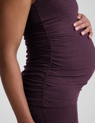 model wearing a purple maternity racerback tank top and leggings against a gray background.