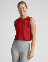 model wearing a red sleeveless top and gray leggings on a plain background.
