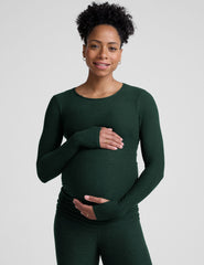 model wearing a green long-sleeve maternity top and leggings against a plain background.