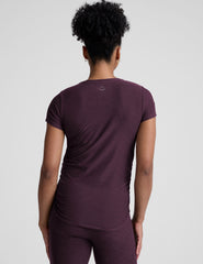 model wearing a purple maternity t-shirt and leggings against a light gray background.