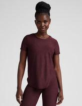 model is wearing a maroon t-shirt and leggings against a plain background.