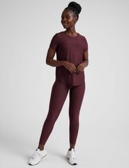 model is wearing a maroon t-shirt and leggings against a plain background.