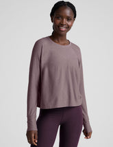 model wearing a light purple scoop neck long-sleeve top and purple leggings on a light gray background.