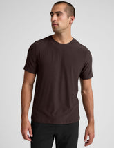 model wearing a brown men's short sleeve t-shirt against a gray background.