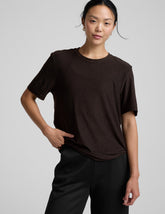 model wearing a brown t-shirt and pants on a light gray background.