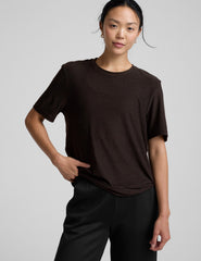 model wearing a brown t-shirt and pants on a light gray background.