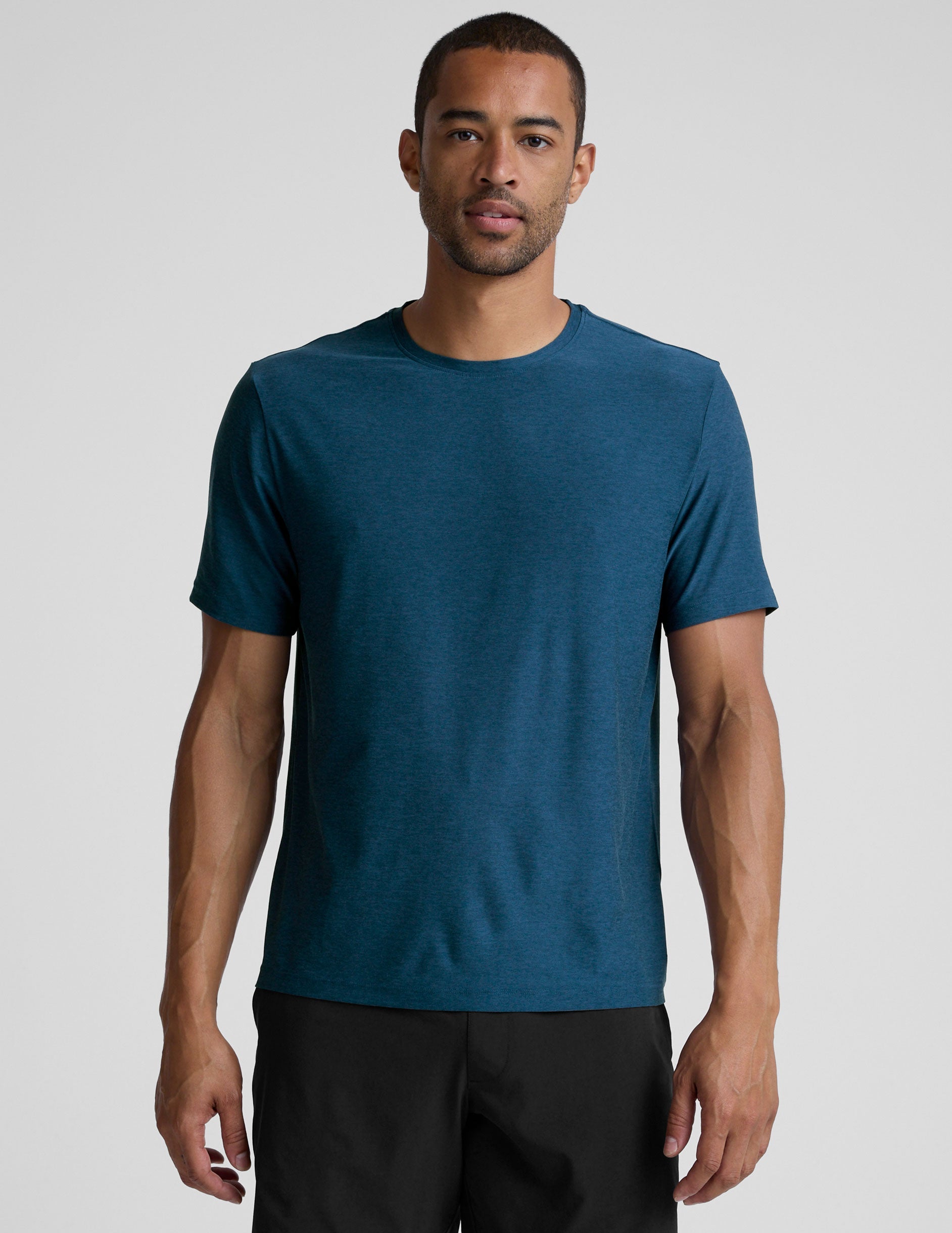 man wearing a blue t-shirt and black shorts against a plain background.