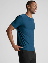 man wearing a blue t-shirt and black shorts against a plain background.
