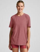 model wearing an oversized men's red t-shirt and shorts on a plain background.