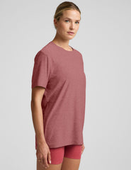 model wearing an oversized men's red t-shirt and shorts on a plain background.