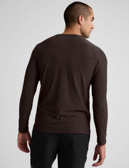 model wearing a brown men's long-sleeve shirt against a gray background.