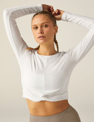 white scoop neck featherweight long sleeve cropped top with a front crossover detail.
