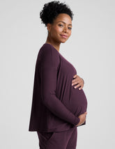 model wearing a purple maternity long sleeve crew neck top and joggers against a light gray background.