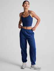 model wearing a blue cropped racerback tank and fleece joggers with pockets on a light gray background.