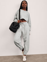model is wearing gray fleece barrel style sweatpants against a plain background.