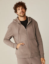 model is wearing a brown men's zip-up hooded jacket.