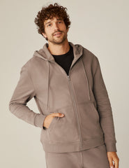 model is wearing a brown men's zip-up hooded jacket.