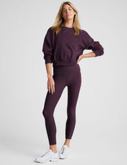 model wearing a purple fleece cropped crew neck sweatshirt and leggings on a light gray background.