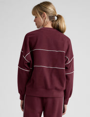 red fleece crewneck sweater with white contrast piping trim at chest and sleeves.