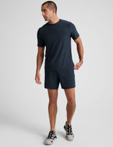 man wearing a navy t-shirt and navy blue lined shorts set on a plain background.