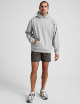 man wearing a gray hoodie and graphite shorts on a white background.