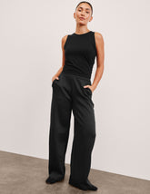 model is wearing a black sleeveless top and black spacer style pants with pockets against a plain background.