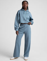 model is wearing blue spacer style pants with pockets against a plain background.