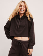 model wearing a brown ribbed cropped hoodie against a plain background.