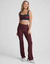 model wearing burgundy pants with a blue stripe on a light gray background.