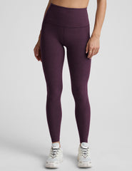 model wearing purple high-waisted full length leggings on a plain background.