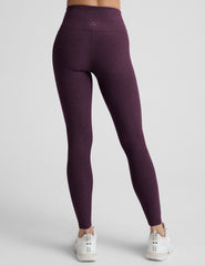 model wearing purple high-waisted full length leggings on a plain background.