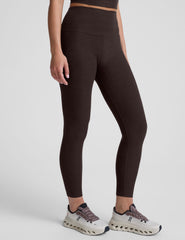 person wearing brown high-waisted midi leggings on a plain background.