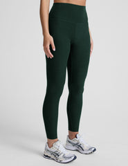 model wearing green high-waisted midi length leggings on a light background.