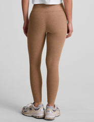 model is wearing brown high-waisted midi leggings and a white tank top.