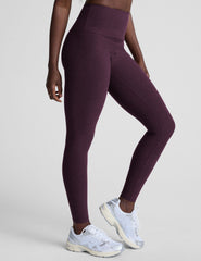 model wearing purple high-waisted midi length leggings on a light background.