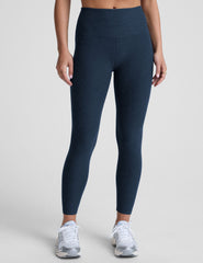 navy blue high-waisted midi leggings worn by model on a light gray background.