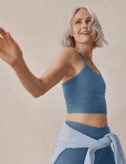 model wearing a blue slim racerback cropped tank and blue high-waisted midi length leggings.