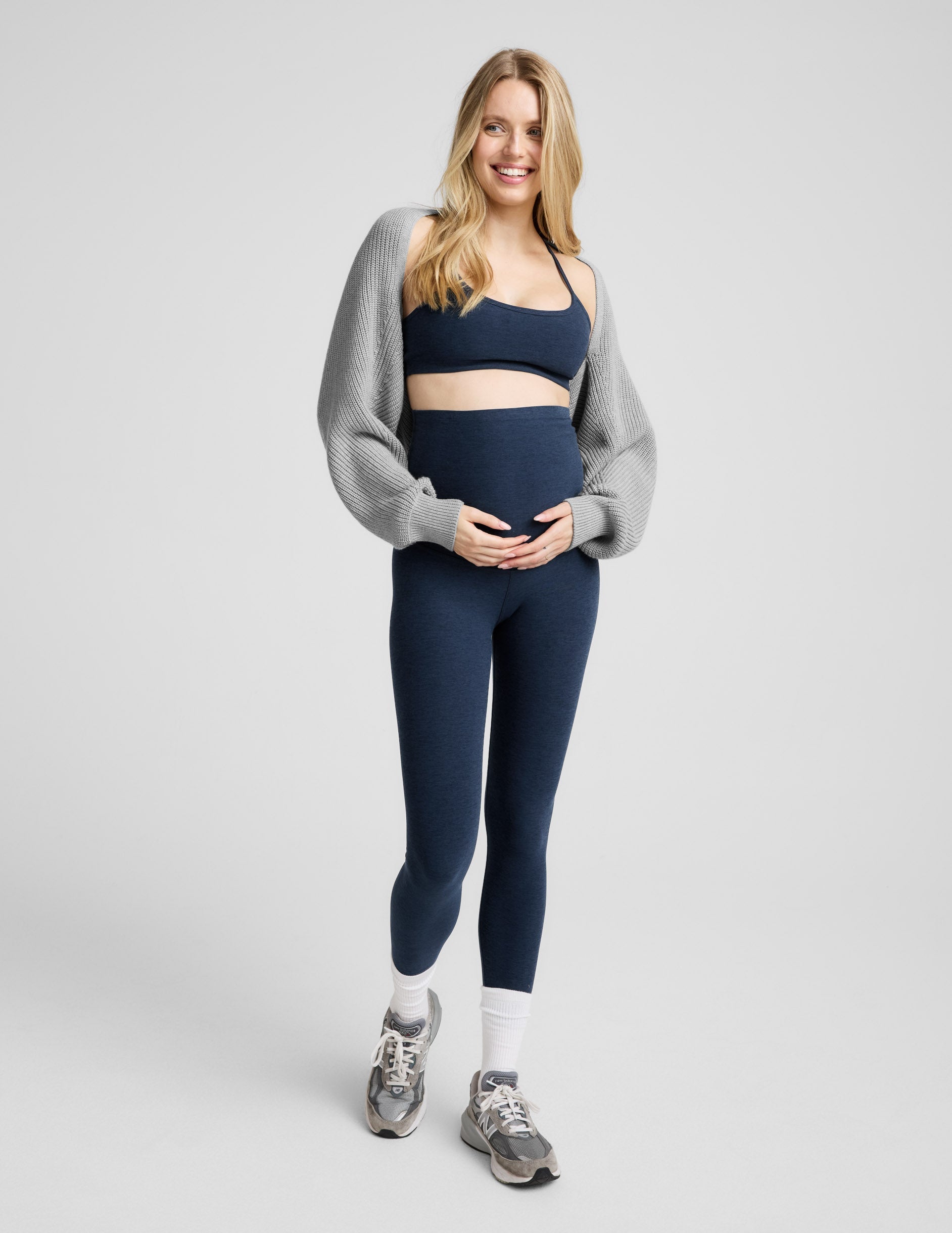 pregnant woman wearing a blue racerback bra and blue maternity midi leggings.