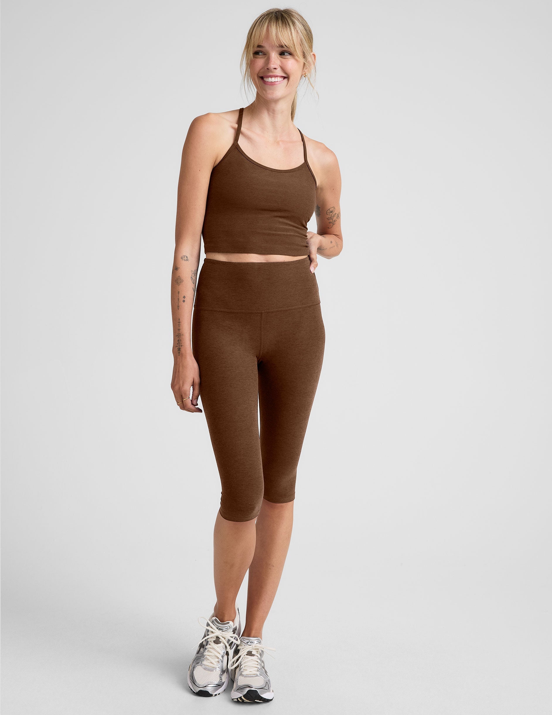 Woman wearing a brown athletic outfit on a white background