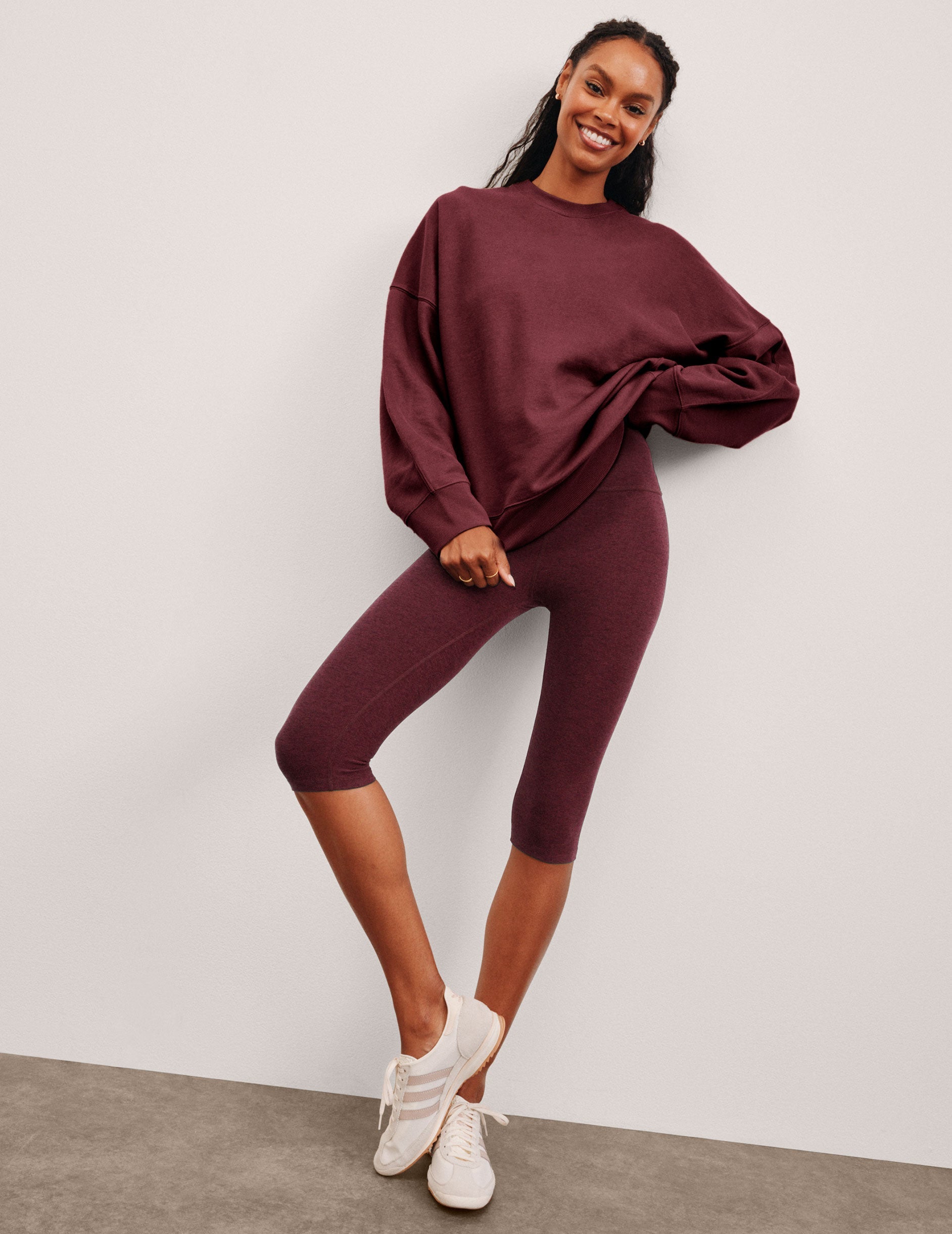 model is wearing red high-waisted pedal pusher length leggings.