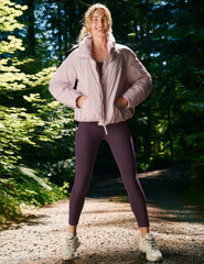 model wearing a pink puffer and purple high-waisted midi length leggings with pockets.