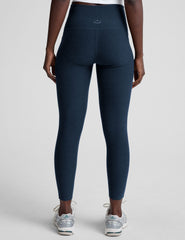 model is wearing blue high-waisted midi length leggings with side pockets on a light gray background.