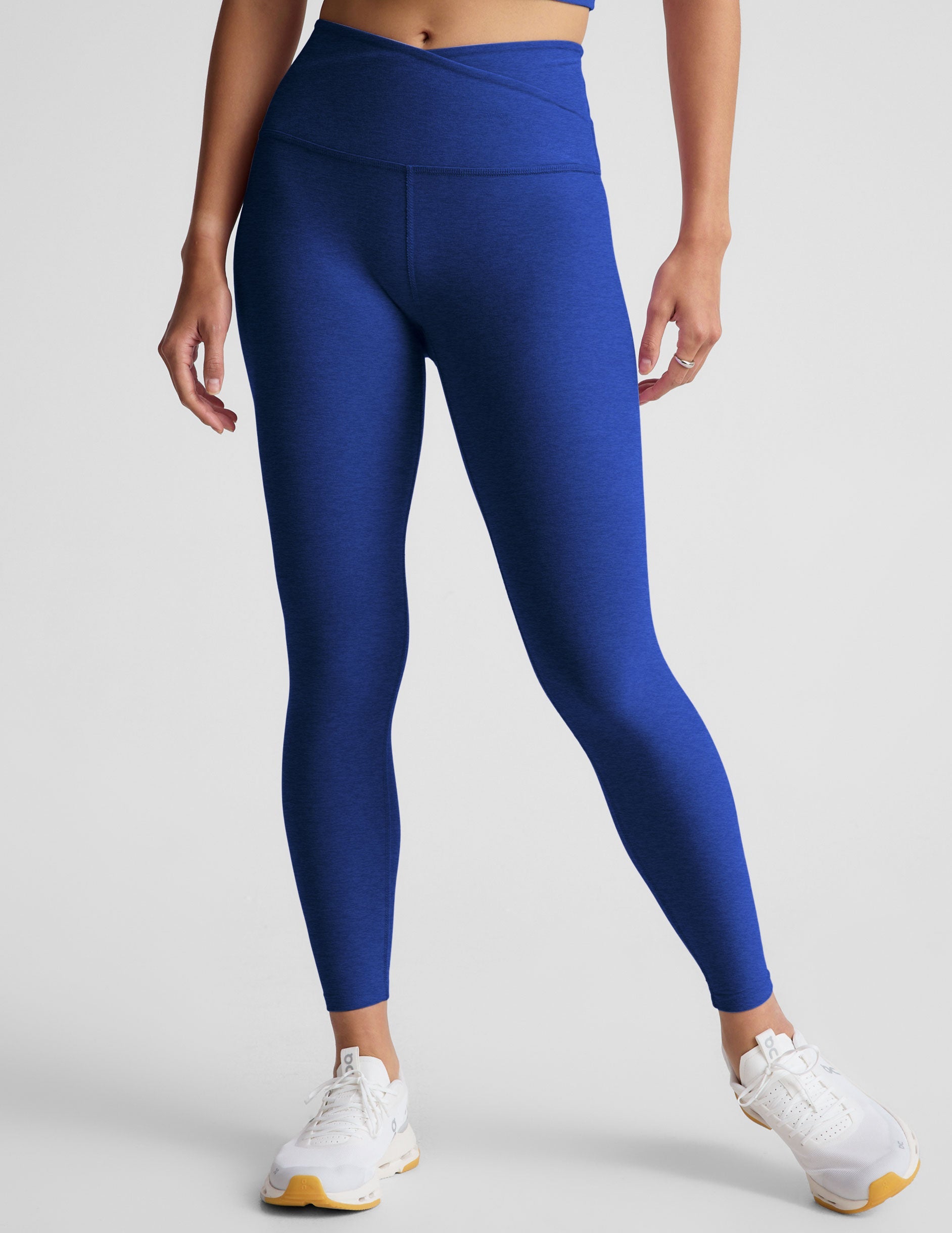 blue high-waisted midi leggings with a crossover detail on the front waistband.