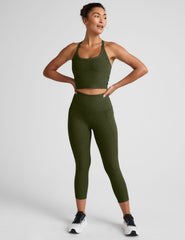 Woman wearing an olive green athletic outfit on a light gray background