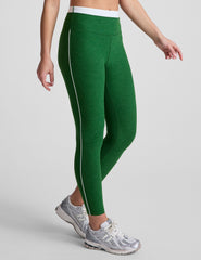 green high-waisted midi leggings with white contrast piping on side of leg and around waistband.