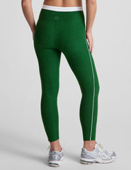 green high-waisted midi leggings with white contrast piping on side of leg and around waistband.