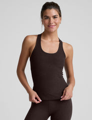 woman wearing a brown racerback and full length tank top and leggings on a plain background.